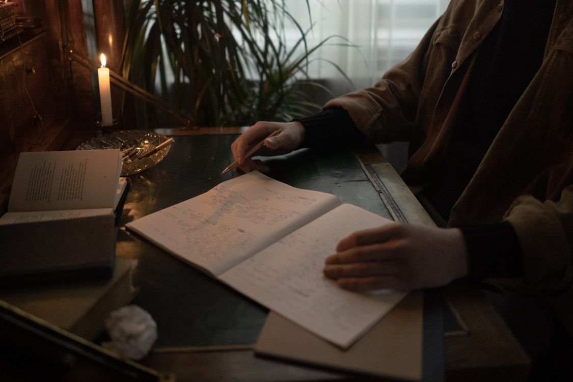 Writer working among books in warm low light